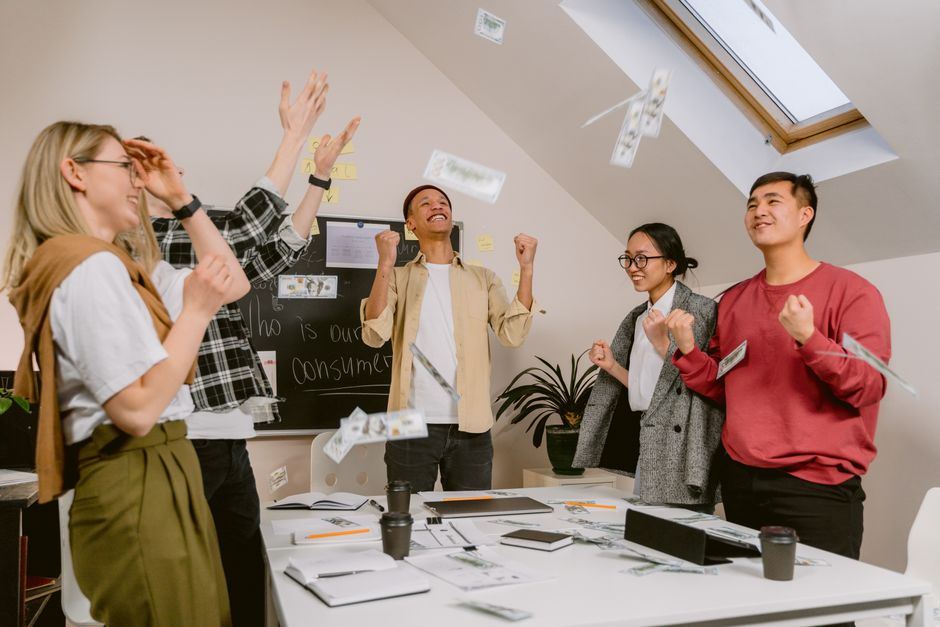 A diverse group of employees celebrating a team achievement in a modern office, showcasing collaboration and positive workplace culture.