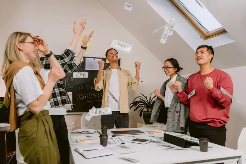 A diverse group of employees celebrating a team achievement in a modern office, showcasing collaboration and positive workplace culture.