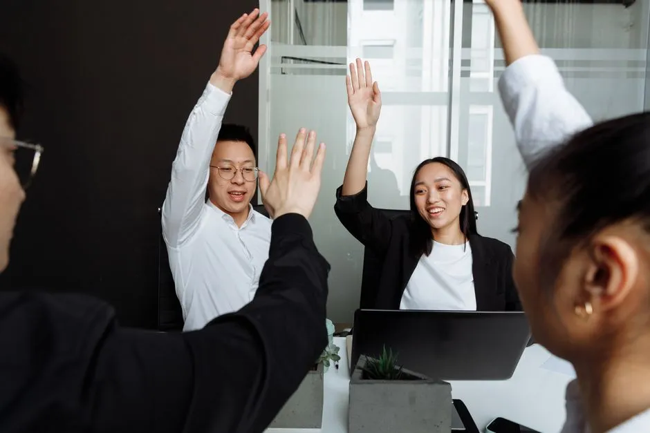 Colleagues high-fiving in a conference room after completing a task - free team building exercises