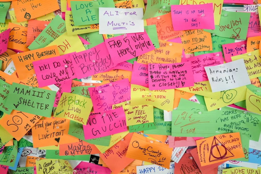 creative physical kudos board covered in colorful sticky notes - peer to peer rewards